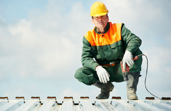 Worker builder roofer at metal profile work